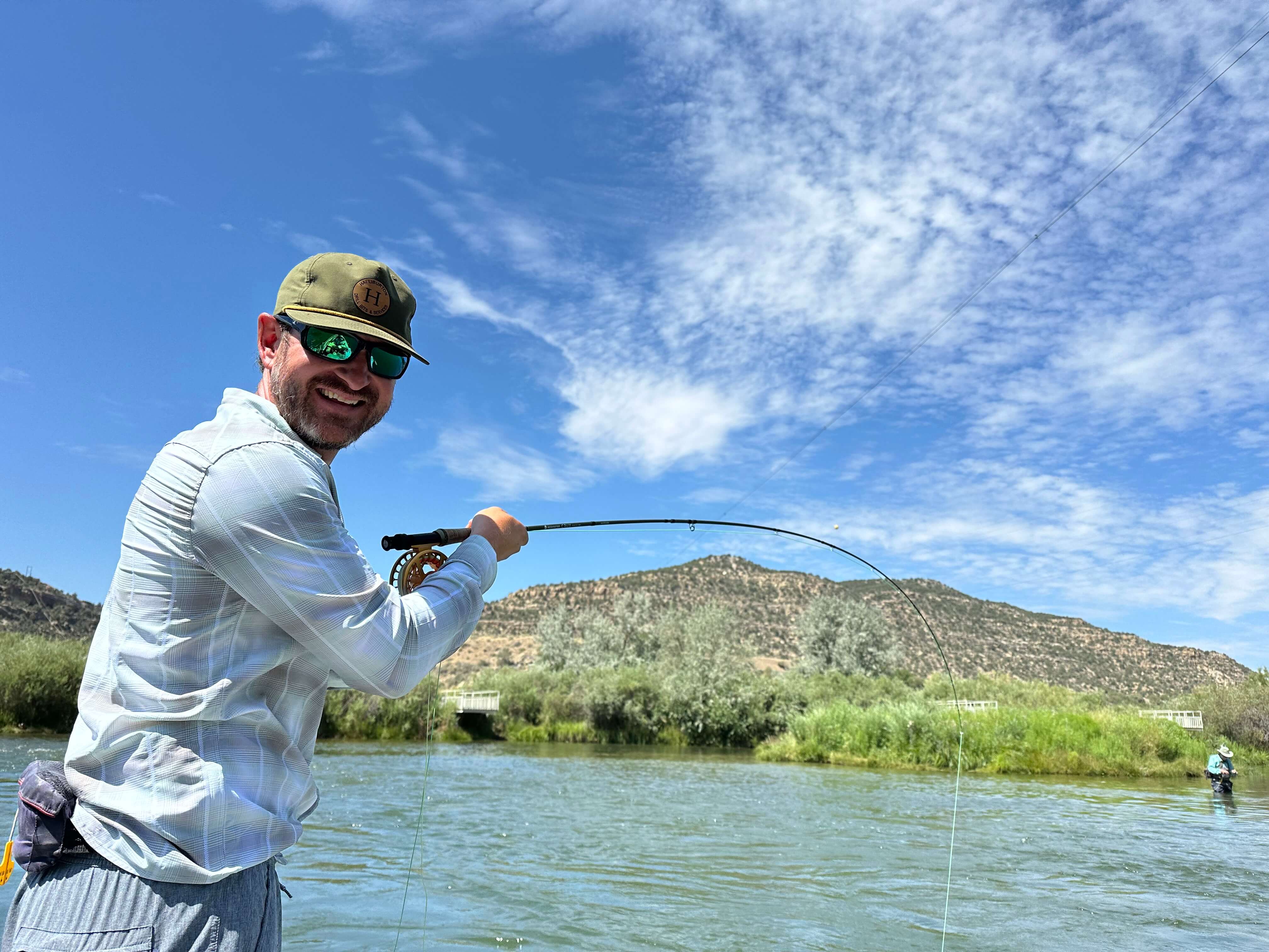 photo of charter client with a big smile and a tight line, bent rod hooked up in the Texas Hole on the San Juan River,NM.